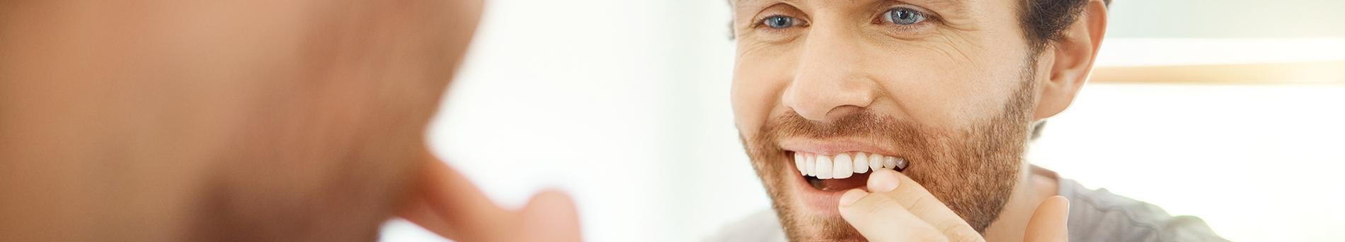 Patient in Mission Viejo smiling in mirror after dental bonding treatment 