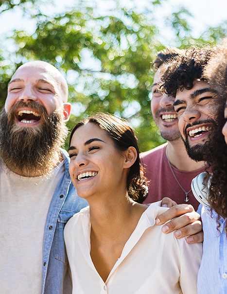 Patient smiling confidently with friends after dental bonding