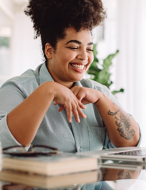 Woman smiling while working on laptop at home