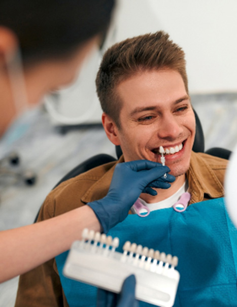 Dentist helping smiling patient select shade of veneers