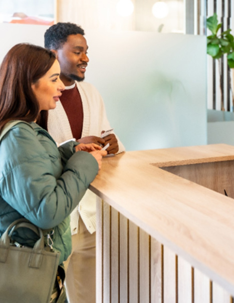 Couple smiling while talking to dental assistant in lobby