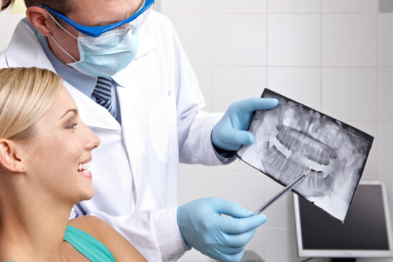 Dentist showing x-ray analysis of teeth to his visitor.